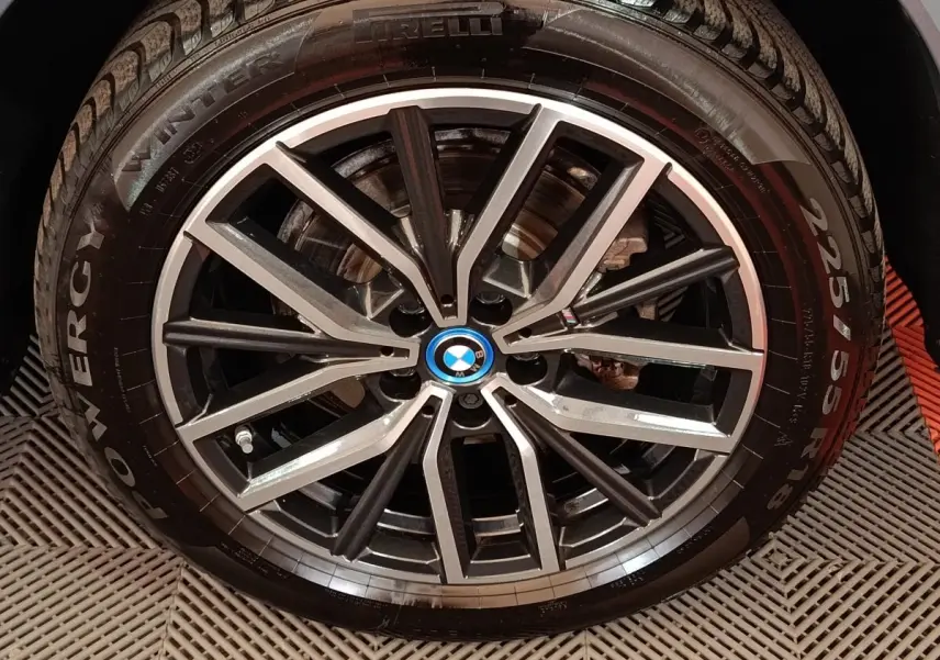 Gros plan sur la jante alliage bicolore noire et argentée avec logo BMW bleu au centre du BMW X1 gris foncé.