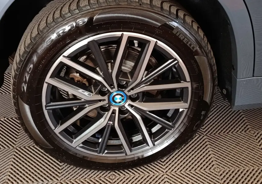 Gros plan sur la jante alliage noire et argentée avec logo BMW d’un BMW X1 xDrive25e gris foncé.