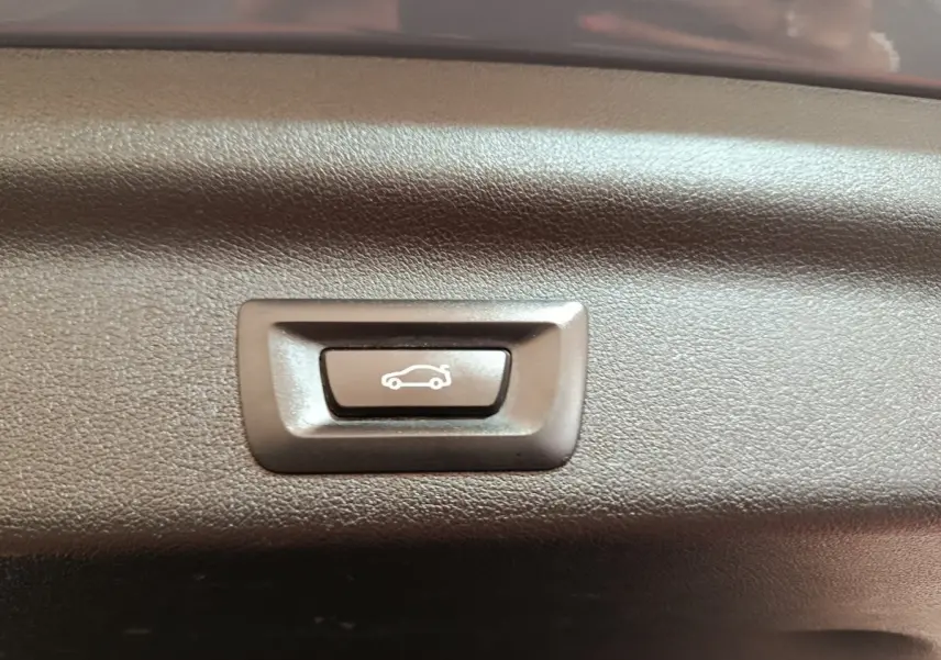 Bouton d'ouverture électrique du coffre sur panneau intérieur d'une BMW X1 xDrive25e M Sport gris foncé 2024.