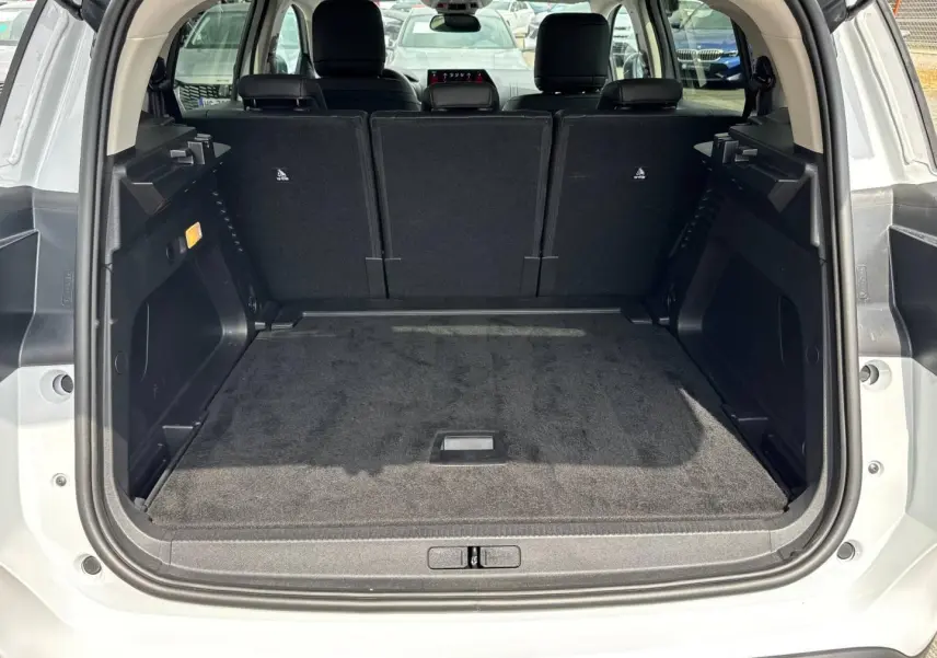 Coffre ouvert vu de l'arrière d'un Citroën C5 Aircross blanc Okénite avec sièges arrière en tissu noir relevés.