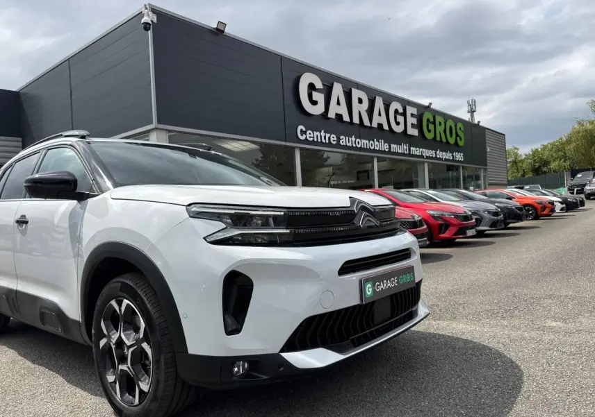 Citroën C5 Aircross blanc Okénite vue 3/4 avant droit avec calandre noire et jantes alu au garage.
