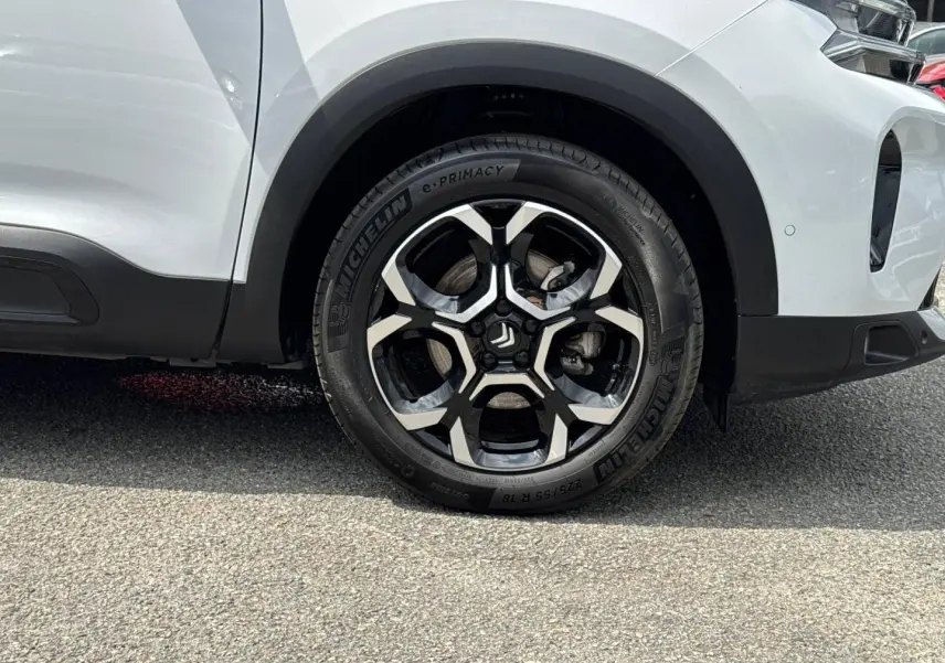 Gros plan sur la roue avant droite d'un Citroën C5 Aircross blanc Okénite avec jante alliage noire et argent.