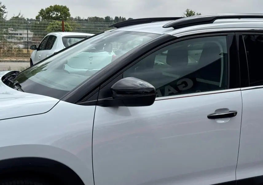 Vue de profil côté gauche sur le CITROEN C5 AIRCROSS blanc Okénite avec barres de toit et rétroviseur noir.