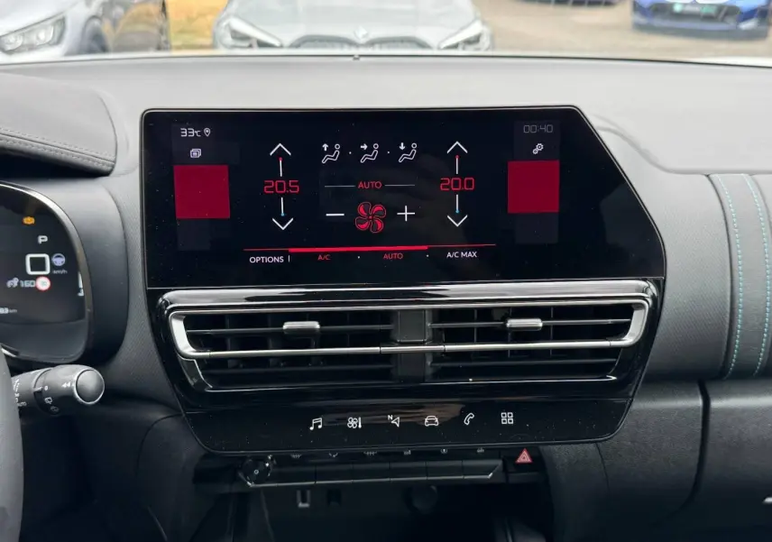 Vue intérieure du tableau de bord du Citroën C5 Aircross 2025, écran tactile avec commandes climatisation et finition noire avec surpiqûres bleues.