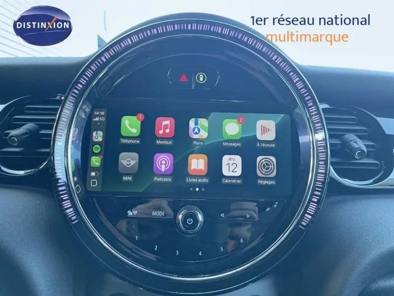 Vue rapprochée de l’écran tactile central rond du tableau de bord de la MINI Cabriolet noire, avec interface Apple CarPlay affichée.