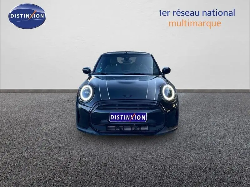 Vue frontale d'une MINI Cabriolet Cooper Midnight Black II avec phares LED ronds allumés sur fond neutre.