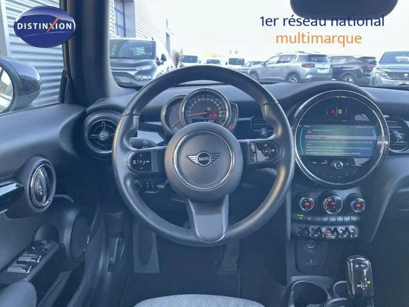 Vue intérieure du tableau de bord et volant cuir noir de la MINI Cabriolet 2023 avec écran tactile circulaire et commandes au volant.