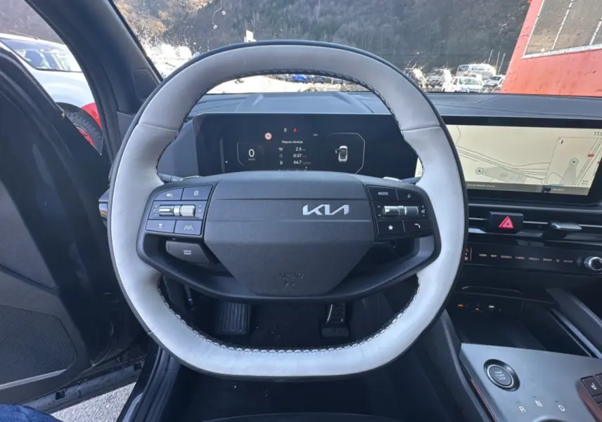Vue intérieure centrée sur le volant cuir clair du KIA Sportage 2026 avec tableau de bord numérique et écran GPS panoramique.