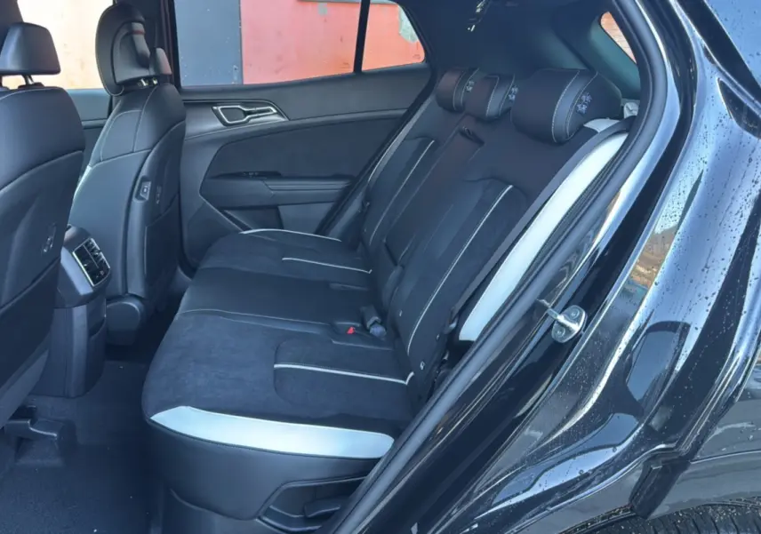 Vue côté droit de l’habitacle arrière du Kia Sportage noir étoilé, avec sièges en cuir noir et surpiqûres blanches.