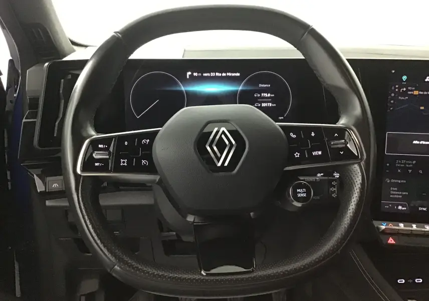 Vue intérieure centrée sur le volant Renault avec commandes intégrées et tableau de bord numérique 12,3 pouces.