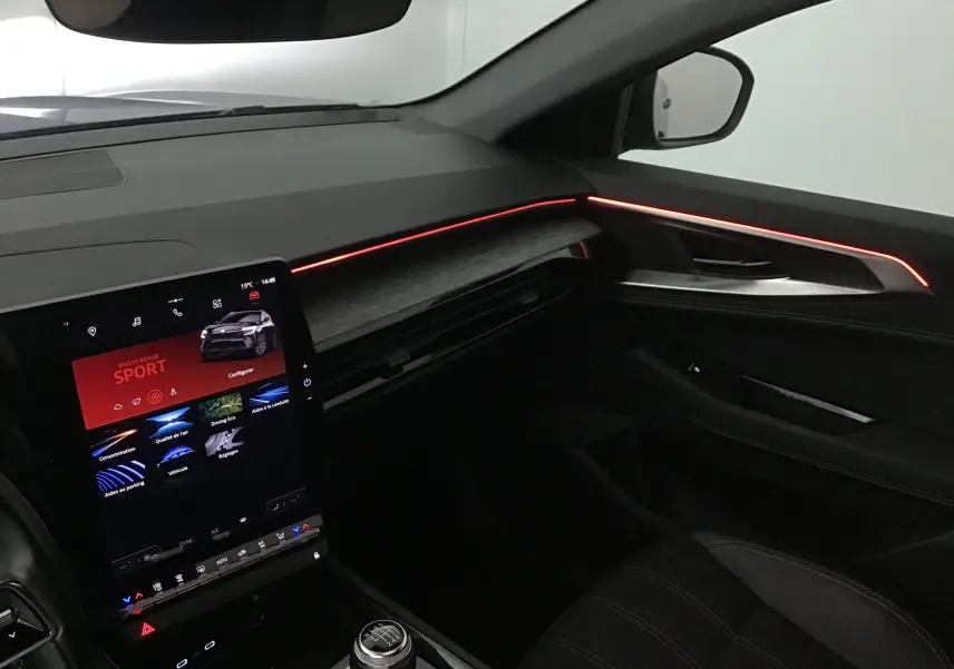 Intérieur côté passager du Renault Austral 2023 avec éclairage d'ambiance rouge et écran tactile vertical.