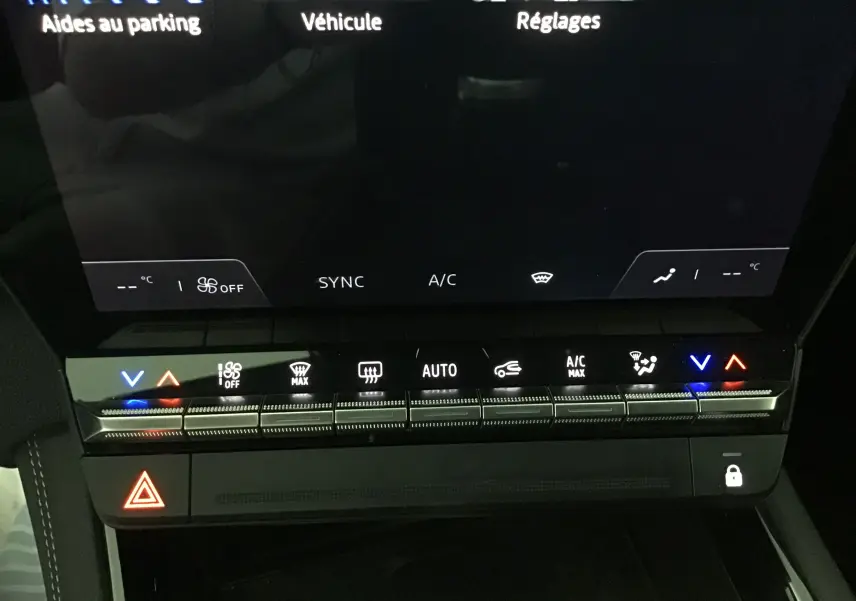Vue rapprochée de la console centrale du Renault Austral bleu iron/noir, mettant en valeur les commandes tactiles de climatisation et l'écran numérique.