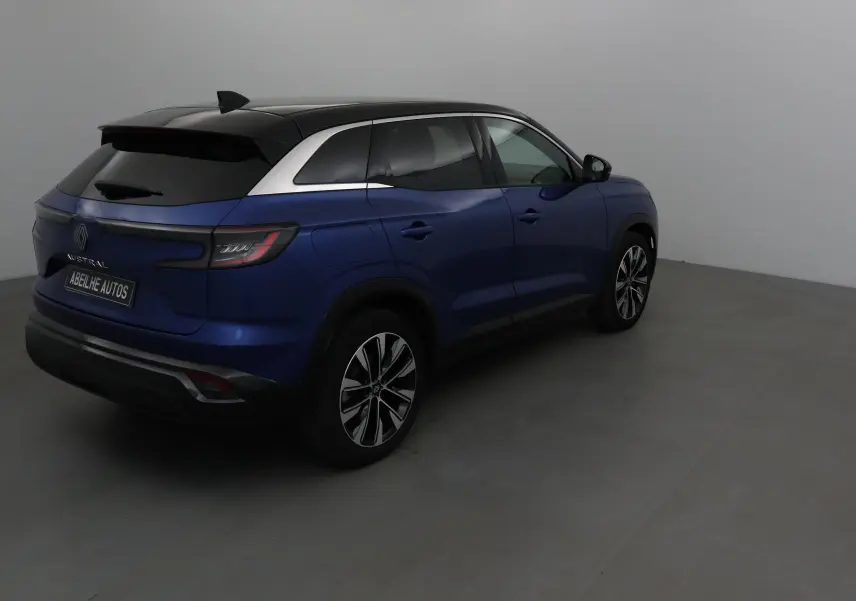 Vue 3/4 arrière droite du Renault Austral bleu Iron avec toit noir et jantes alliage 19 pouces dans un studio.