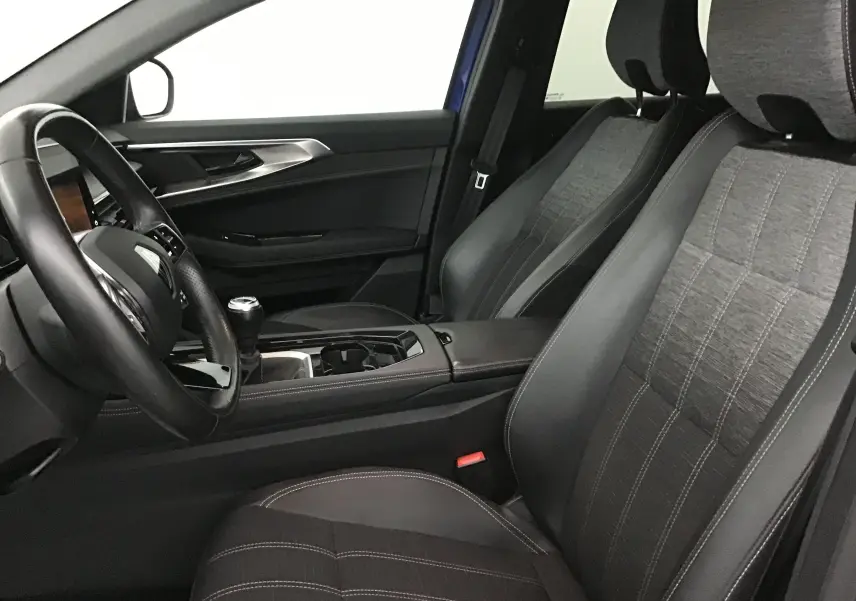 Intérieur avant droit du Renault Austral 2023, sièges tissu et cuir noirs, volant cuir et levier de vitesse manuel visibles.