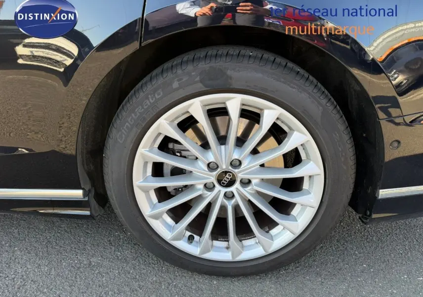 Gros plan sur la roue avant droite de l'Audi A8 noire Sebring Cristal, mettant en valeur la jante aluminium multibranches.