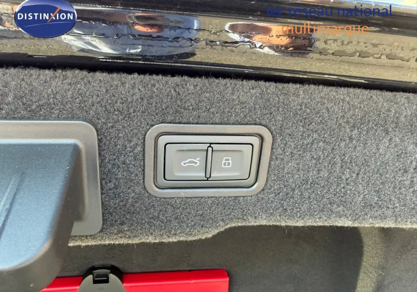 Gros plan sur les boutons d'ouverture et de verrouillage du coffre d'une Audi A8 noire Sebring Cristal, intérieur du coffre visible.