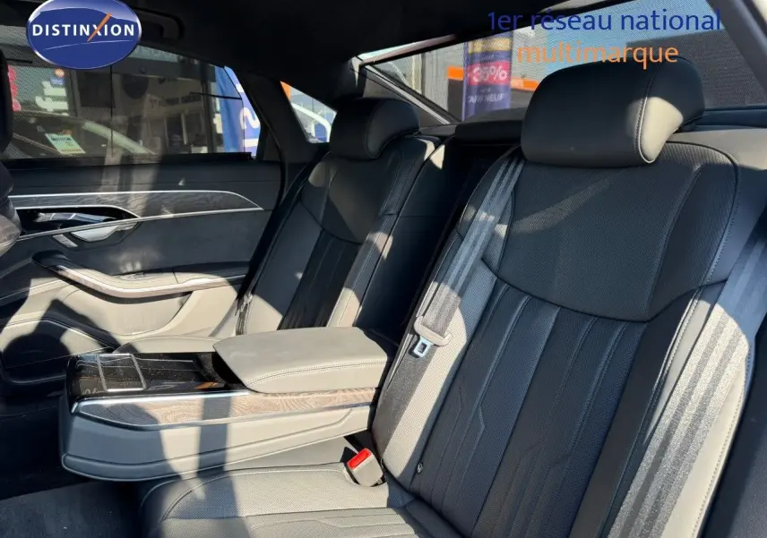 Intérieur arrière de l'Audi A8 2024 noir Sebring Cristal, sièges en cuir noir et accoudoir central avec rangement.
