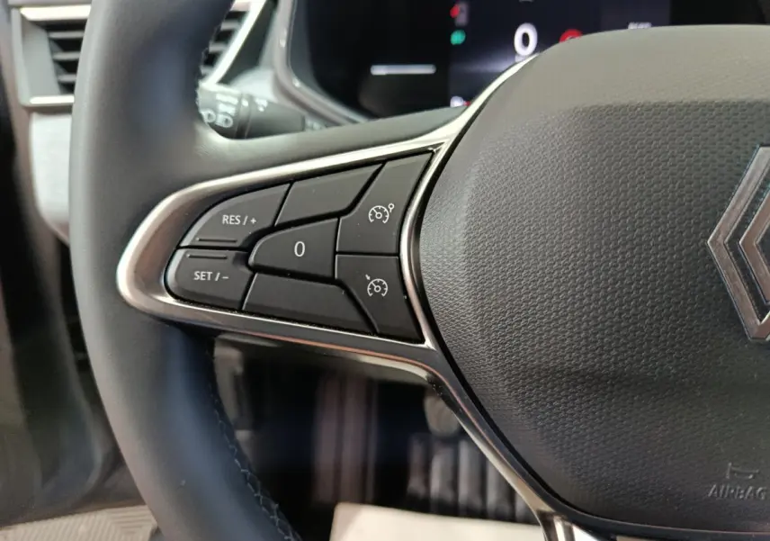 Gros plan sur le volant noir de la Renault Clio 2025 avec commandes de régulateur de vitesse visibles à gauche.