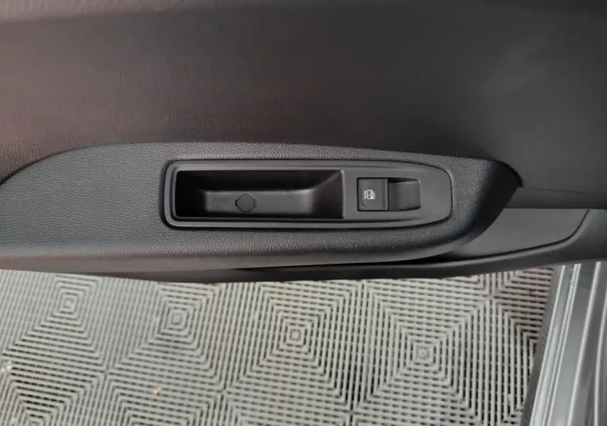 Bouton de verrouillage des portes sur la portière côté droit d'une Renault Clio gris foncé, vue intérieure rapprochée.