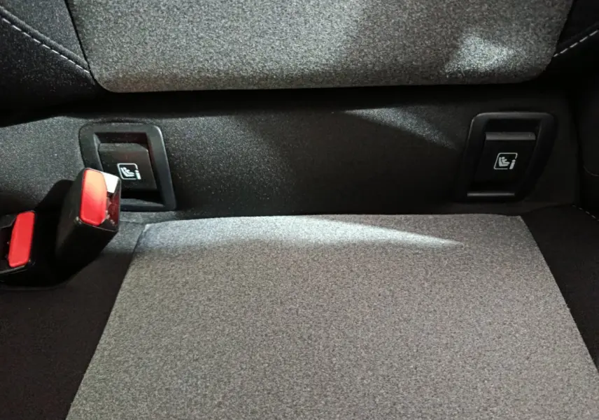 Détail de la banquette arrière grise de la Renault Clio 2025 avec attaches Isofix et boucles de ceinture rouges.