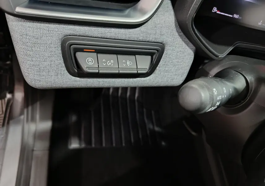 Détail des commandes d'éclairage et verrouillage côté gauche du tableau de bord gris clair de la Renault Clio gris foncé 2025.