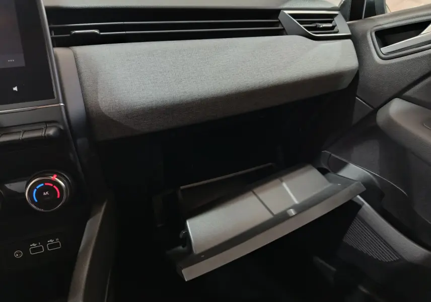 Intérieur de la Renault Clio Evolution Blue dCi 100 2025, vue côté passager sur la boîte à gants ouverte et tableau de bord gris foncé.
