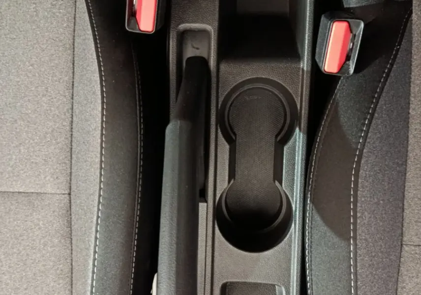 Vue plongeante sur la console centrale noire et les sièges gris foncé de la Renault Clio Evolution 2025 avec frein à main manuel.