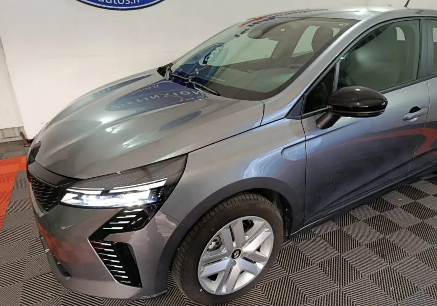 Vue 3/4 avant droit d'une Renault Clio gris foncé avec phares LED et rétroviseurs noirs brillants.