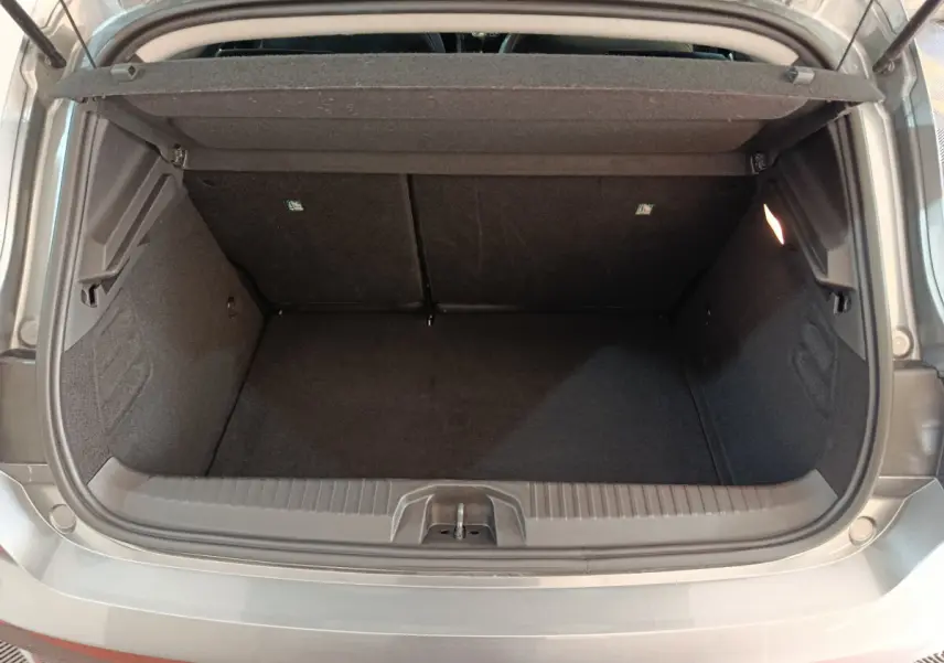 Coffre ouvert gris foncé de la Renault Clio Evolution Blue dCi 100 2025, montrant un espace de chargement vide et éclairé.