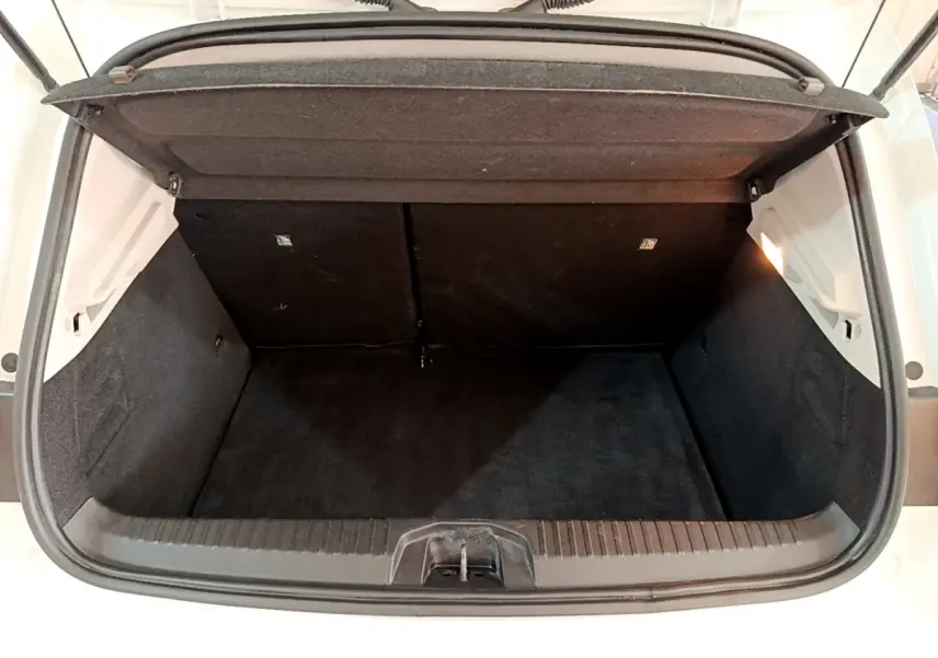 Coffre ouvert vu de l'arrière d'une Renault Clio Business Blue dCi 115 blanche, intérieur noir et éclairage latéral.