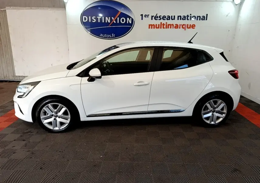 Profil droit d'une Renault Clio Business Blue dCi 115 blanche, avec jantes alliage et vitres teintées, en intérieur showroom.