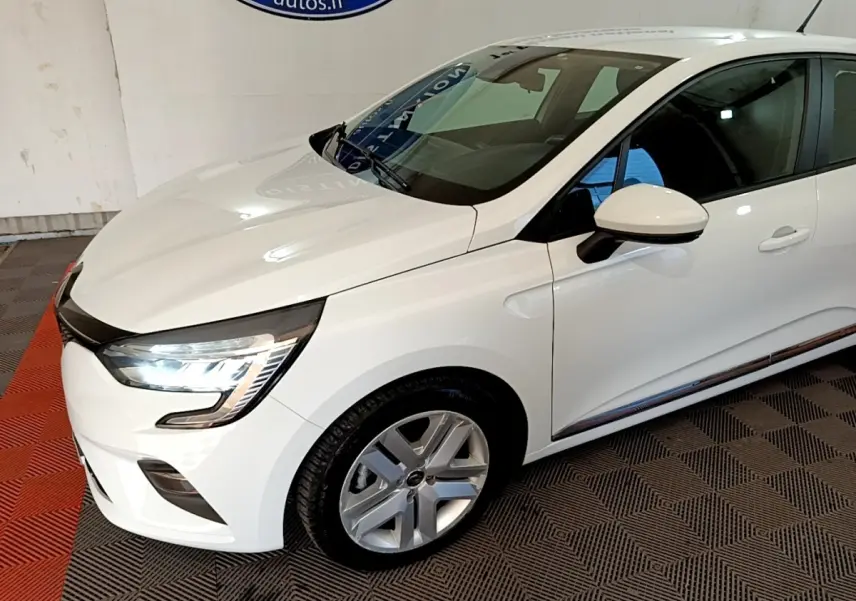 Vue 3/4 avant droite d'une Renault Clio Business Blue dCi 115 blanche avec phares LED allumés et jantes alliage.