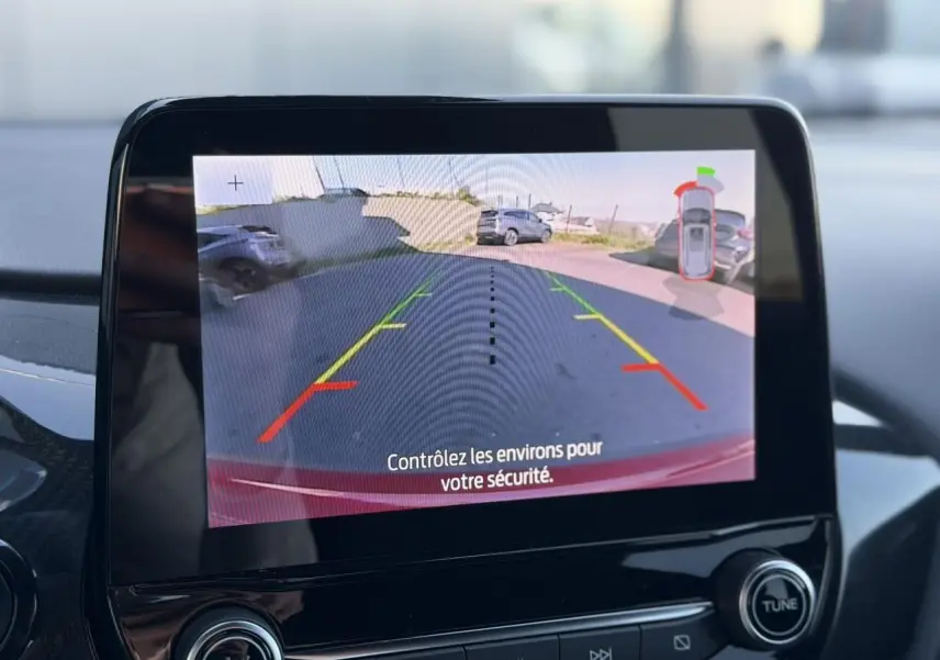 Écran tactile intérieur montrant la caméra de recul 180° du Ford Puma rouge, avec lignes d’aide au stationnement.
