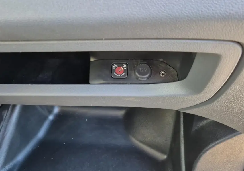 Détail de la console centrale du Citroën Jumpy blanc 2019 montrant une prise 12V et un interrupteur rouge.