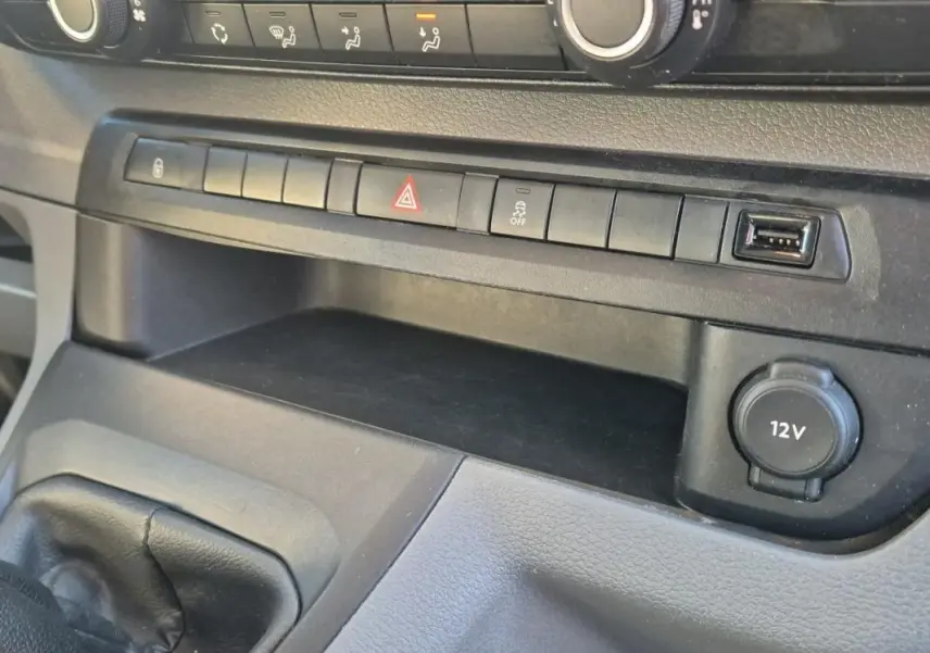 Détail de la console centrale du Citroën Jumpy blanc 2019, montrant les boutons de commande et prise 12V.