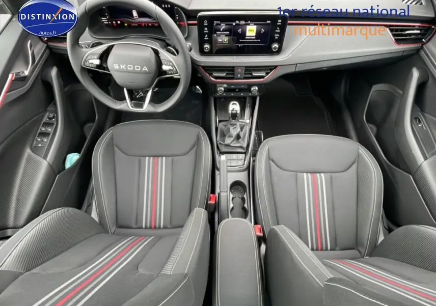Vue intérieure frontale du Skoda Kamiq noir 2026, mettant en valeur le volant cuir, les sièges sport à bandes rouges et la console centrale.