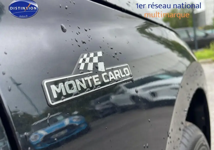 Gros plan sur l'écusson Monte Carlo sur l'aile avant droite d'un Skoda Kamiq noir brillant avec gouttes de pluie.