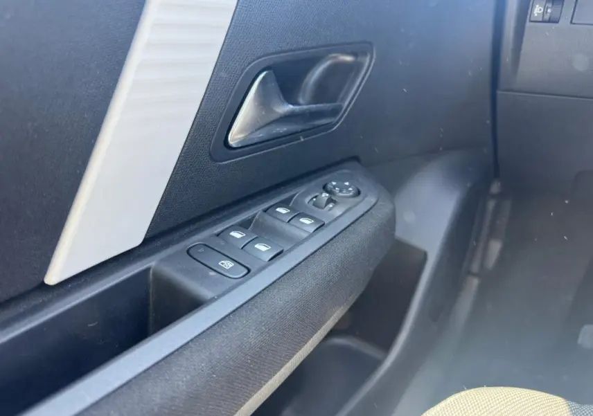 Détail de la porte côté conducteur de la Citroën C4 hybride blanche, avec commandes électriques des vitres et rétroviseurs.