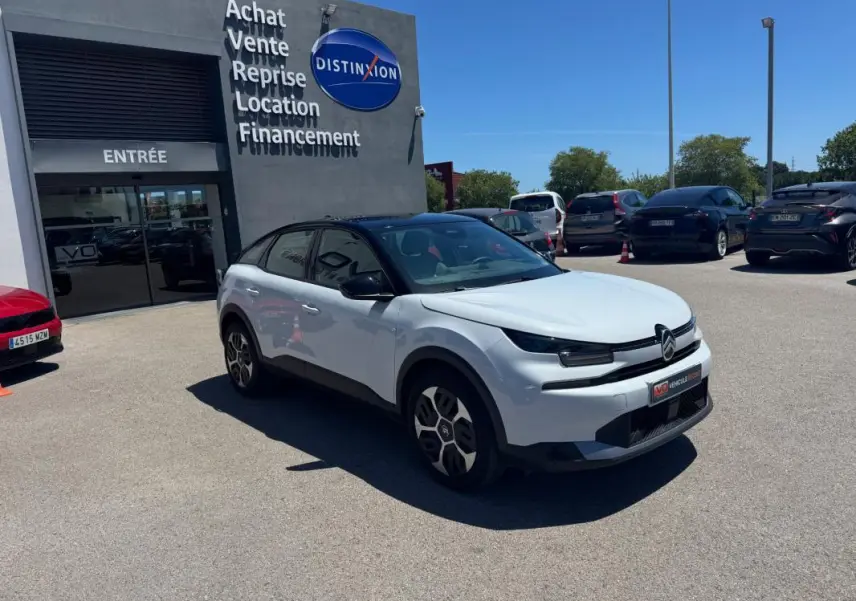 Citroën C4 hybride blanc vue 3/4 avant droit, toit noir, jantes alliage 18 pouces, stationnée devant un concessionnaire.