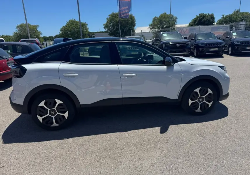 Vue de profil côté gauche d'une Citroën C4 hybride blanche avec toit noir et jantes alliage 18 pouces.