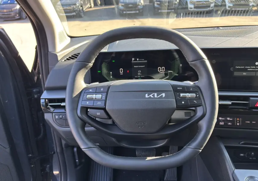 Vue centrée sur le volant cuir multifonctions du Kia Sportage gris eclipse avec tableau de bord numérique et écran tactile.