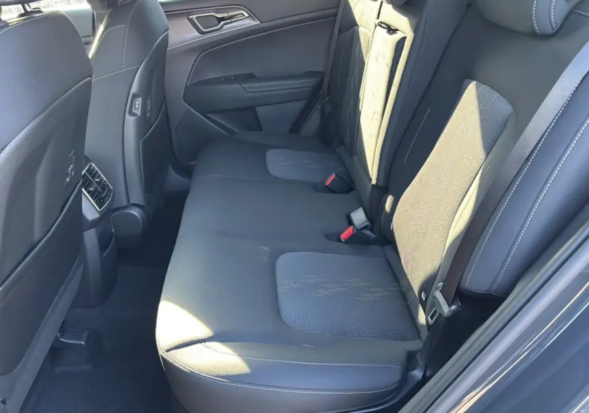 Vue côté droit de la banquette arrière en tissu gris du Kia Sportage 2026, avec ceinture de sécurité et porte arrière ouverte.