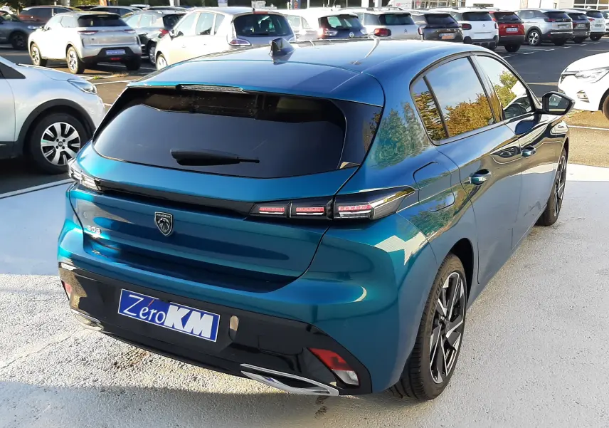 Vue 3/4 arrière droite d'une Peugeot 308 Bleu Obsession 2025 avec vitres teintées et feux LED distinctifs.