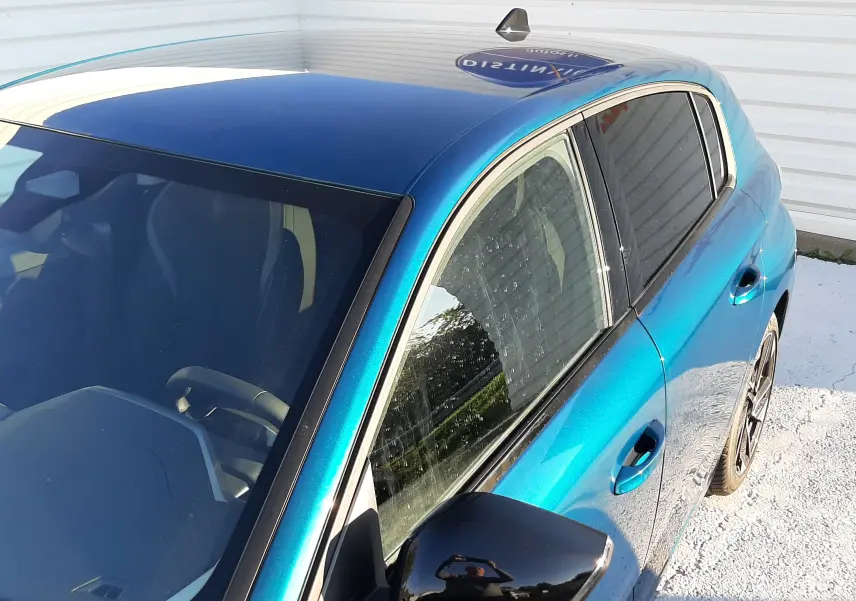 Vue 3/4 avant droit d'une Peugeot 308 Bleu Obsession avec rétroviseur noir brillant et vitres teintées.