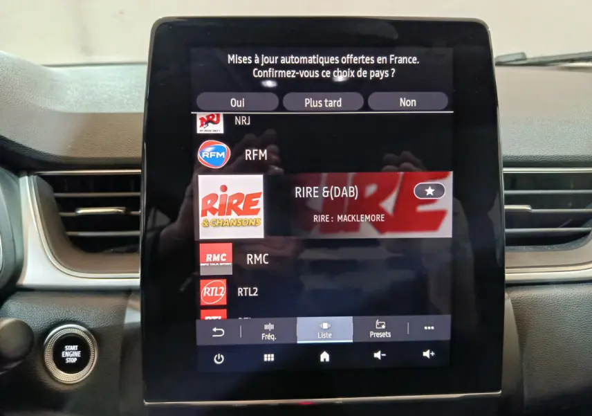 Écran tactile central du tableau de bord du Renault Captur rouge 2024 affichant les stations radio numériques.