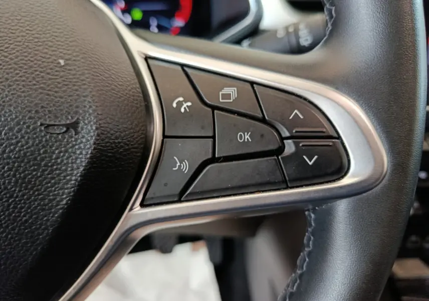 Gros plan sur les commandes multifonctions noires du volant côté gauche du Renault Captur rouge 2024.