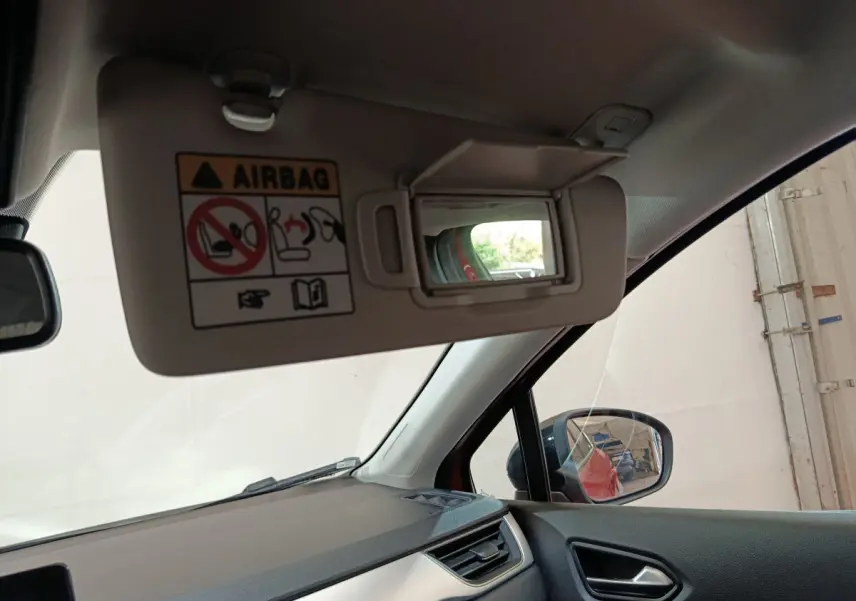 Vue intérieure côté conducteur du Renault Captur rouge 2024, avec pare-soleil baissé et miroir de courtoisie visible.