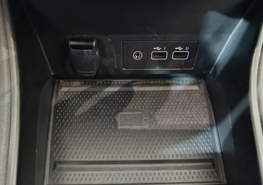 Gros plan sur la zone de recharge sans fil et les ports USB avant du Renault Captur rouge Techno TCe 90 2024.