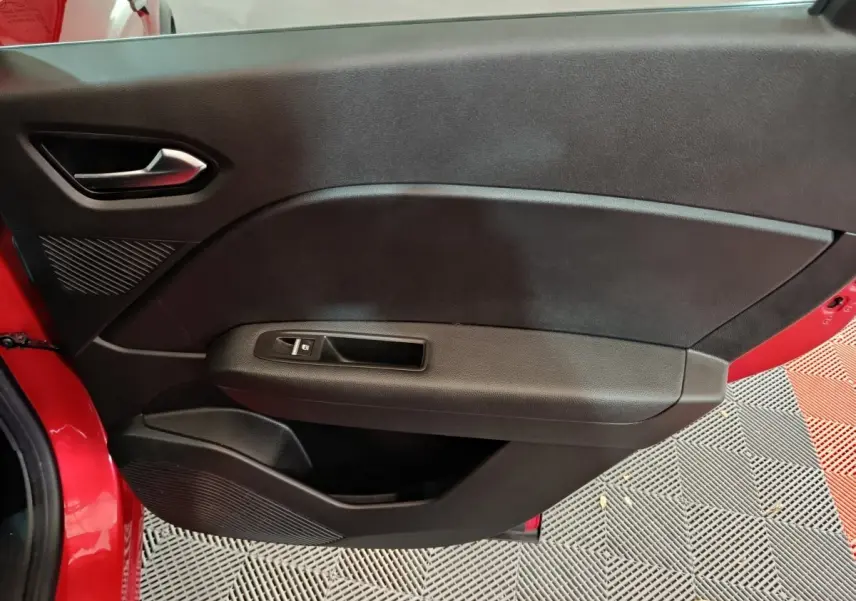 Porte intérieure côté gauche noire avec poignée argentée et bouton de lève-vitre sur Renault Captur rouge 2024.