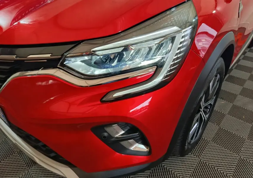 Gros plan sur le phare avant droit du Renault Captur rouge 2024 avec détails chromés et jante visible.